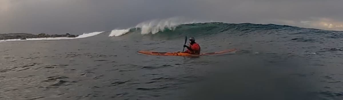 Panorama of a paddler in front of a line of breaking waves