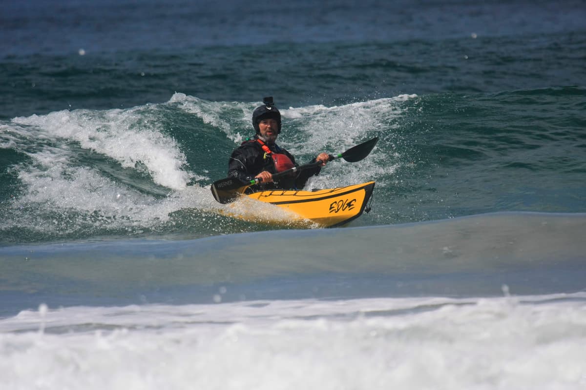 Paddler surfing a wave in a yellow sea kayak in Hoddevik