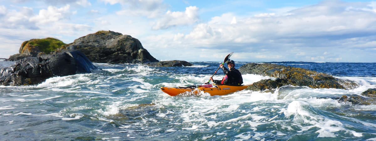 Paddler in surf among skerries, panorama