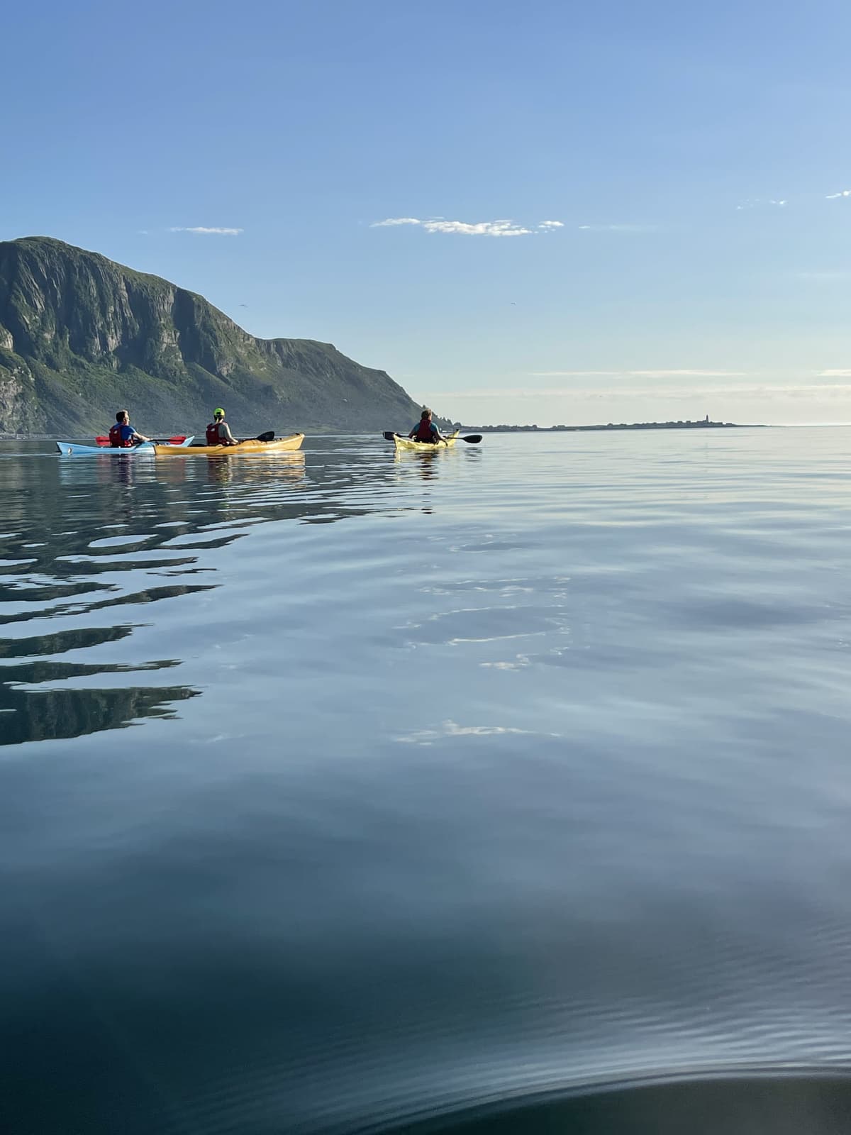 Group paddling towards the mountains on mirror-calm water