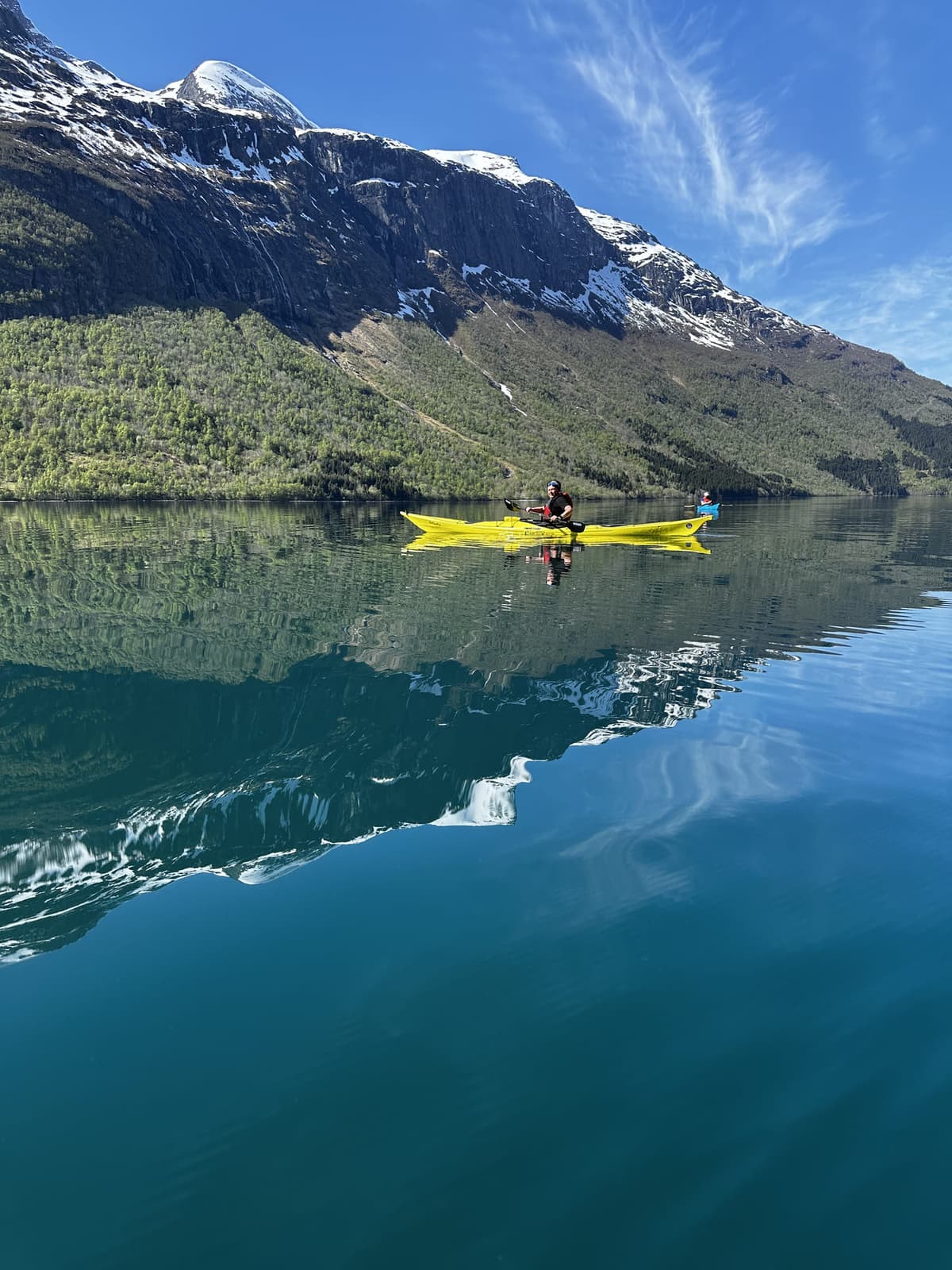 Kayak below a snow-capped mountain reflected in turquoise water
