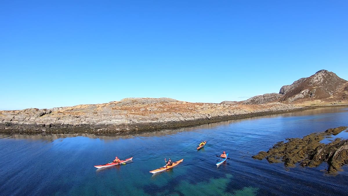 Kayaks in turquoise water between islets under a blue sky