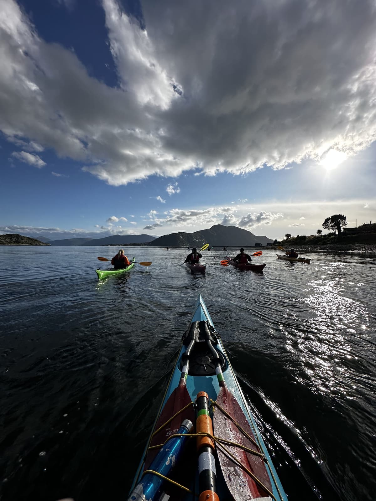 Paddling group on the fjord under a dramatic cloudy sky