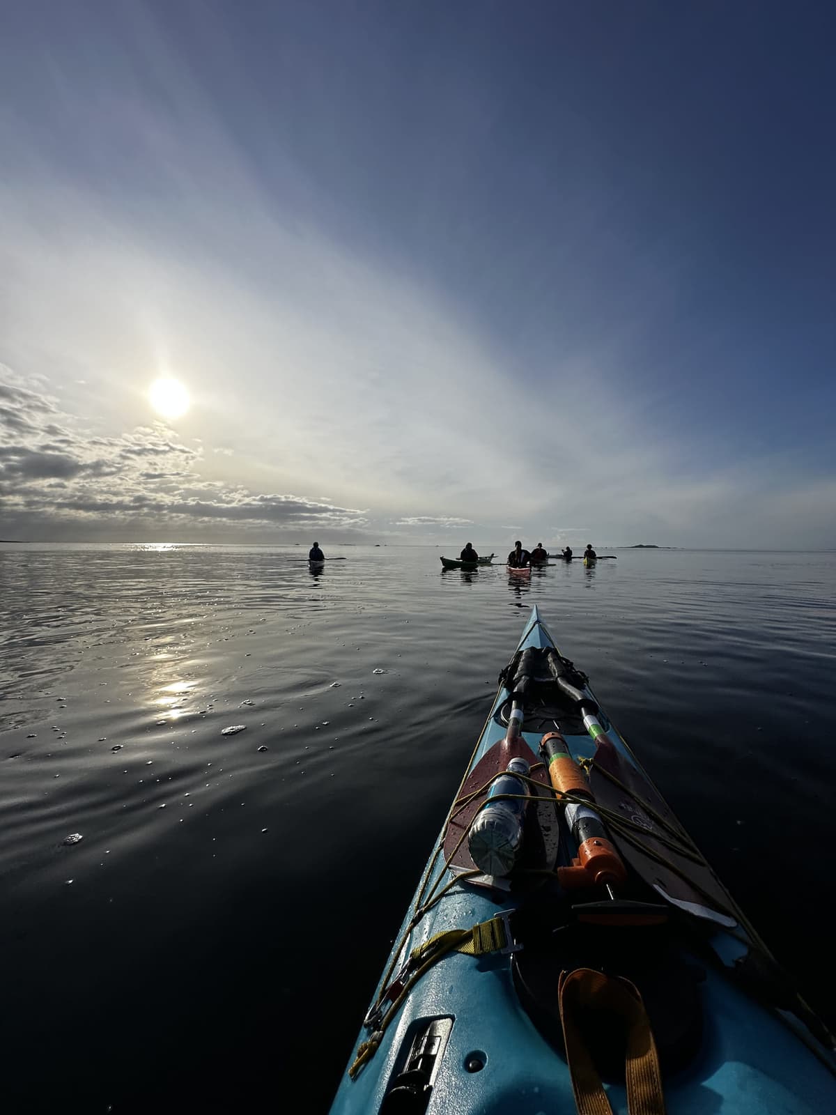 Paddling group backlit with sun reflecting on the sea