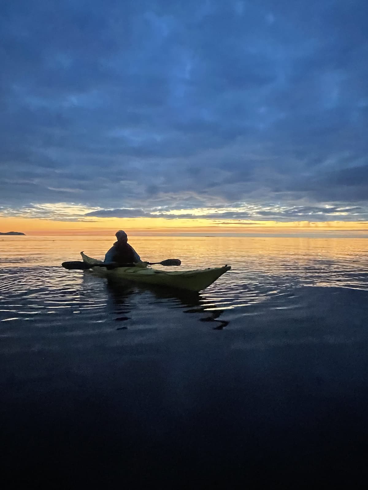 Paddler silhouetted against a golden sunset