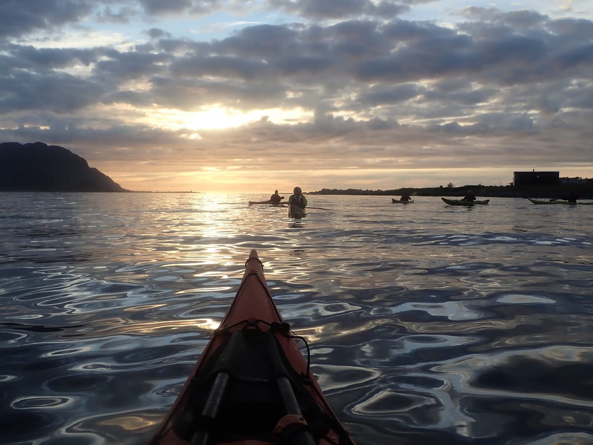 Sunset behind the mountains with a paddling group on the water