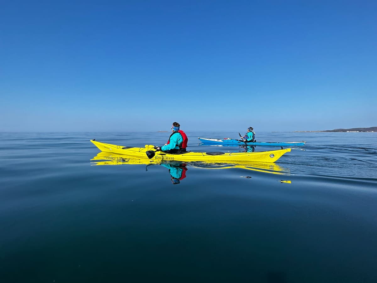 Two yellow sea kayaks on deep blue, glassy water