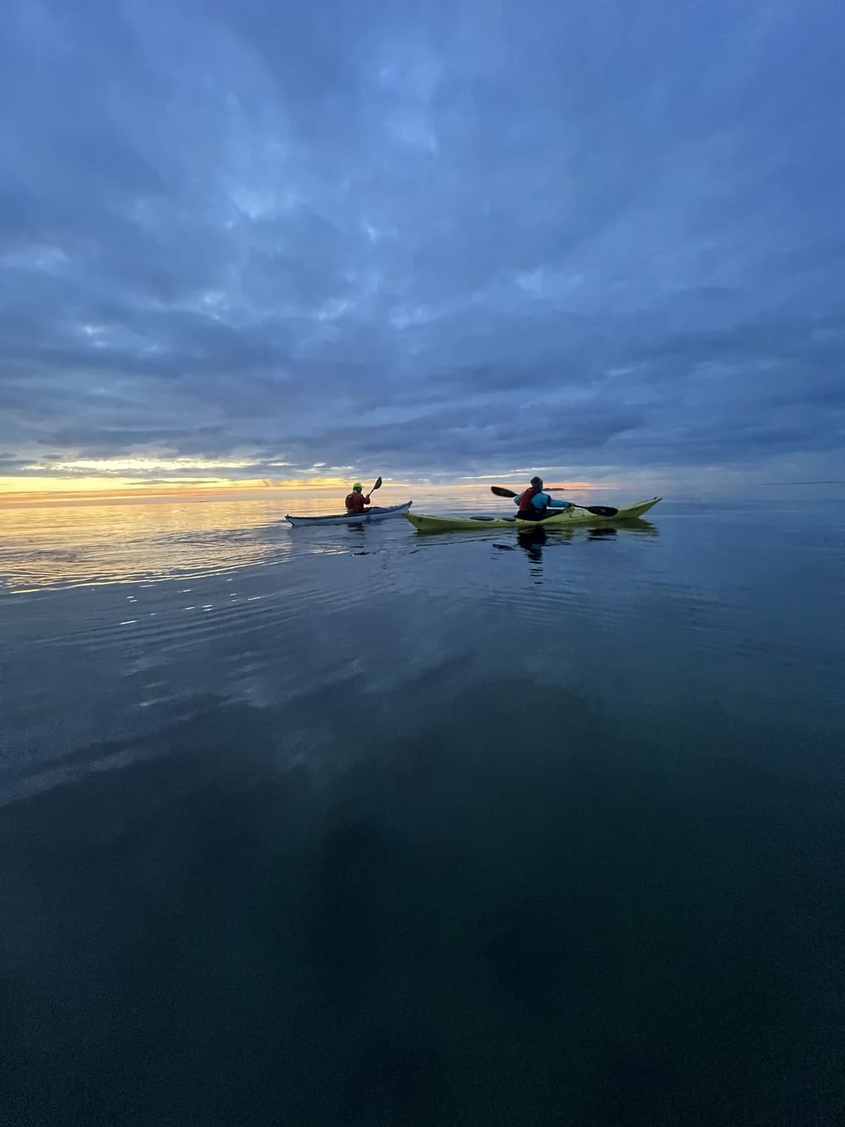Two paddlers in the blue hour with a golden horizon