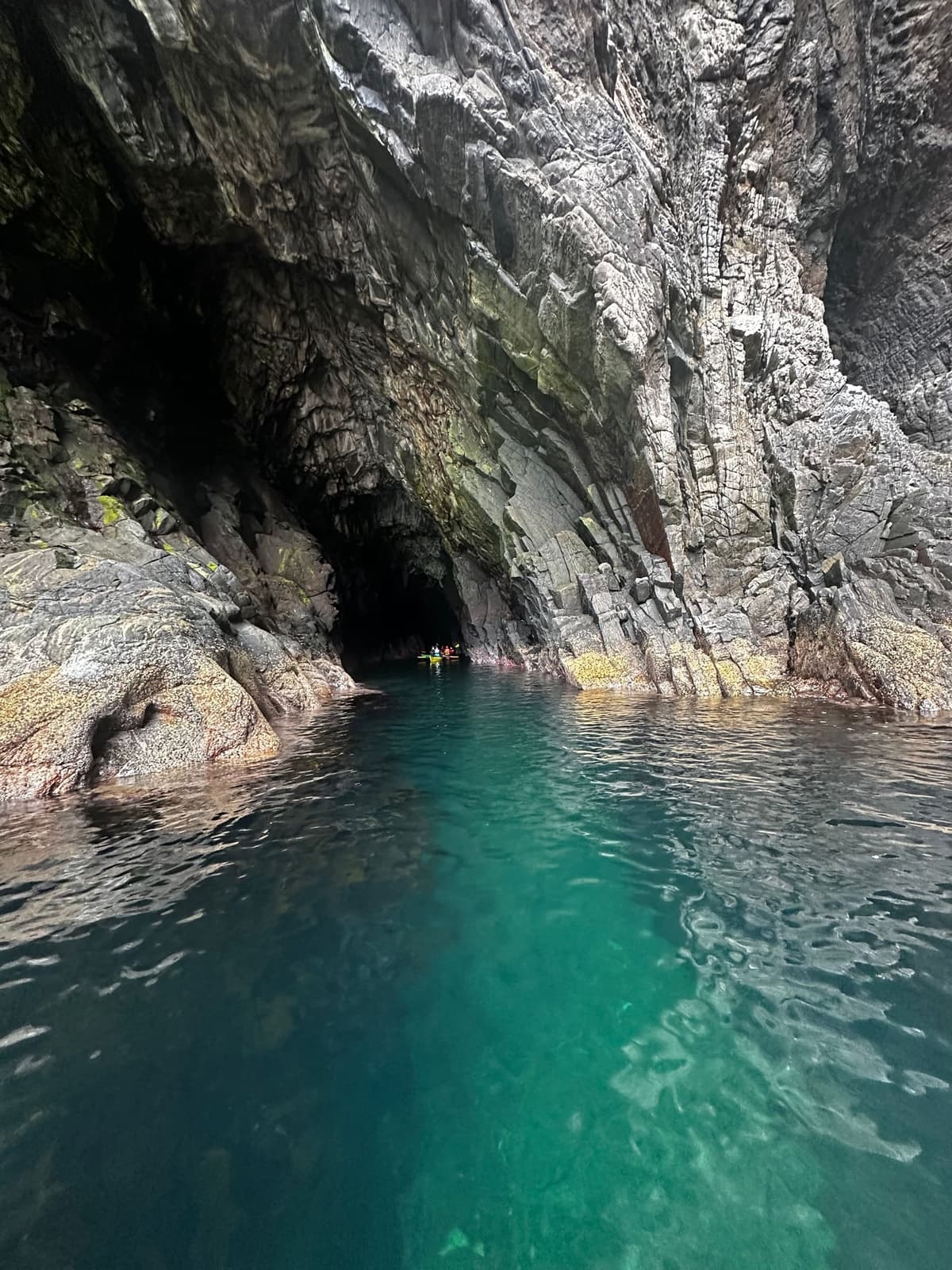 Kajakkpadler utforsker en sjøgrotte med turkist vann på Runde